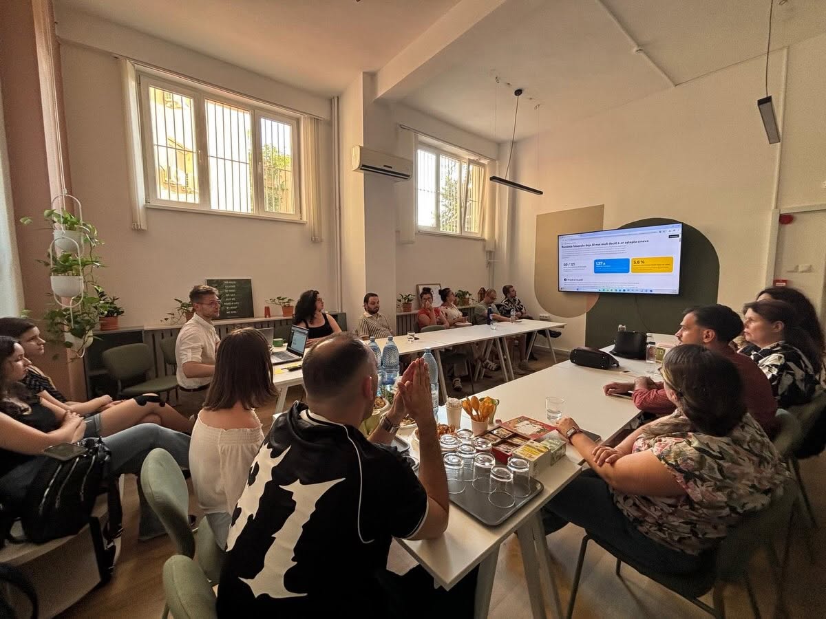 Grup de participanți urmărind o prezentare scurtă pe ecran