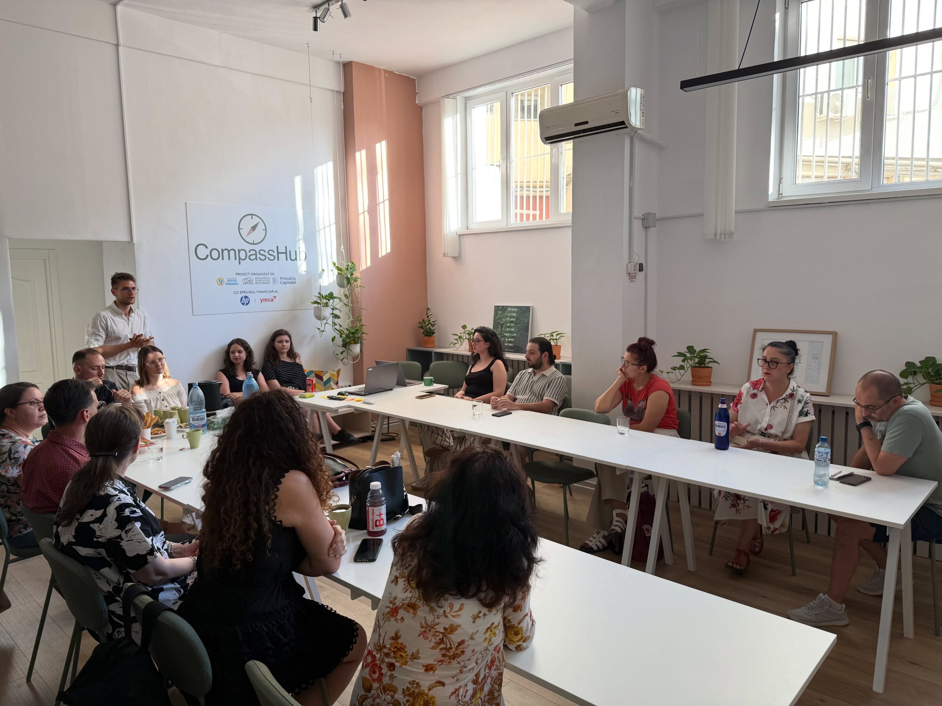 Participanți așezați la mese lungi la CompassHub Iancului, în timpul primei ediții